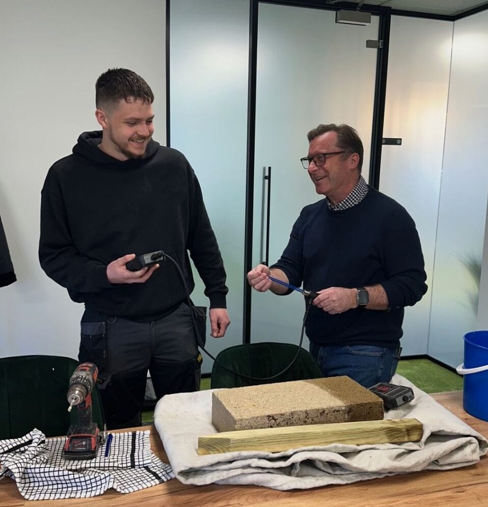 An instructor showing a student how to use moisture measuring equipment. 