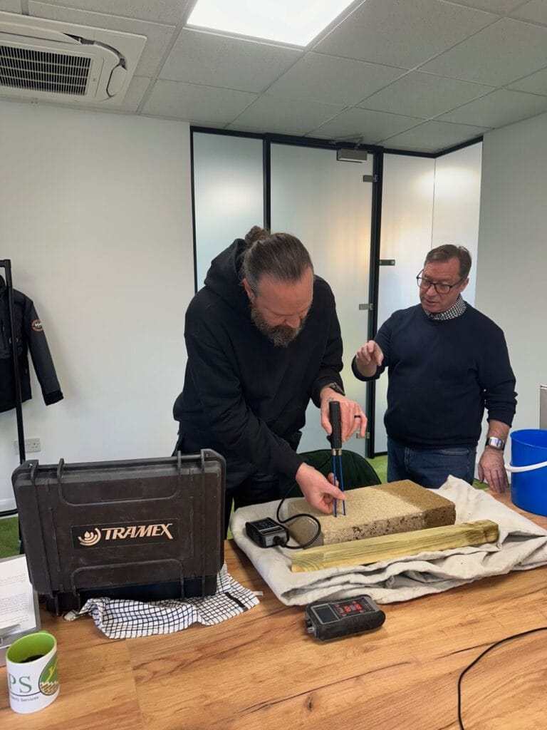 An instructor showing a tradesman how to correctly take moisture readings.